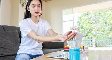 donna d'affari asiatica che lavora da casa e si sta pulendo le mani con gel disinfettante per il coronavirus protettivo. È messa in quarantena a casa durante l'epidemia di coronavirus. foto