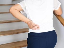 donna tailandese con dolore lombare, mal di schiena, dolori muscolari salendo le scale. foto