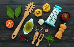 la pasta su fondo di legno nero. pasta italiana gialla con ingredienti. cibo italiano e concetto di menu. foto