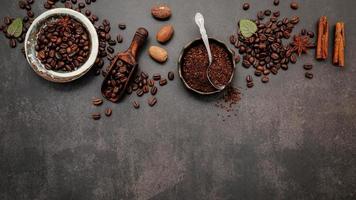chicchi di caffè tostati con polvere di caffè e ingredienti saporiti per preparare gustosi caffè su sfondo di pietra scura. foto