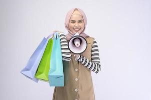 giovane bella donna musulmana in tuta con borse della spesa colorate su sfondo bianco studio foto