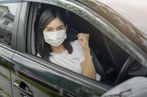 giovane bella donna che indossa una maschera protettiva alla guida di un'auto foto