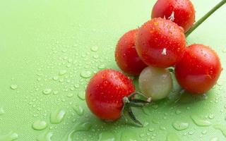 pomodori freschi con gocce su un tagliere verde foto