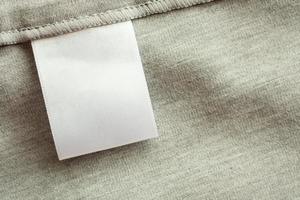 etichetta di abbigliamento per la cura della lavanderia in bianco bianco su sfondo grigio di struttura del tessuto foto
