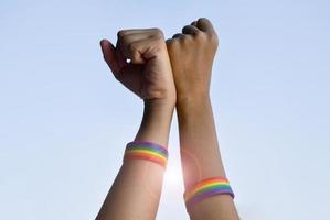 braccialetti di gomma arcobaleno nei polsi di una coppia di ragazzi asiatici con sfondo sfocato, concetto per la celebrazione della comunità lgbt nel mese dell'orgoglio o nel giugno in tutto il mondo. foto