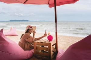 videochiamata felice giovane donna con gli amici in spiaggia foto