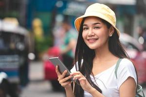 la donna asiatica del viaggiatore si rilassa il viaggio con lo smartphone nella città di bangkok. foto