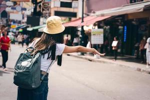 vista posteriore donna asiatica chiama un taxi per i viaggi in città. foto