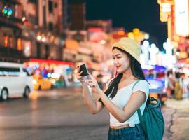 giovane donna asiatica con smart phone. sfondo della strada khaosan. foto