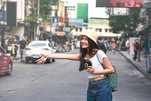 donna asiatica, scendi da un taxi a Bangkok con la fotocamera istantanea foto