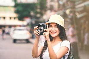 donna asiatica del viaggiatore con la macchina fotografica istantanea a khaosan foto