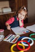 la bambina sveglia disegna un cerchio di vernici colorate foto