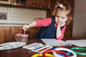 la bambina sveglia disegna un cerchio di vernici colorate foto