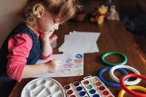 la bambina sveglia disegna un cerchio di vernici colorate foto