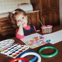 la bambina sveglia disegna un cerchio di vernici colorate foto