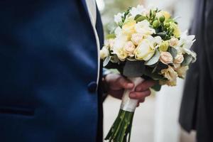 bouquet da sposa nelle mani dello sposo foto