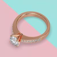 anello solitario di fidanzamento in oro rosa con pietre laterali su gambo rendering 3d foto