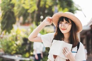 giovane viaggiatore donna asiatica che scrive l'elenco del diario nel taccuino sul viaggio in programma. foto