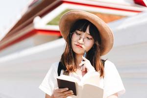 nota della donna del viaggiatore asiatico del giovane adulto per la guida foto