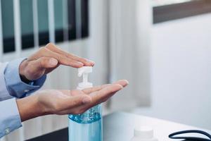 il medico premette la mano sulla bottiglia di disinfettante per le mani. foto