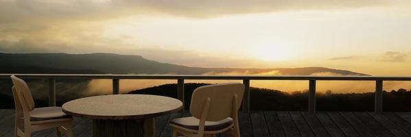 tavoli e sedie in legno per rilassarsi sul balcone o terrazzo con assi di legno. il ristorante sulla montagna ha una vista sulla collina e sulla foschia alla luce del sole del mattino. rendering 3D foto