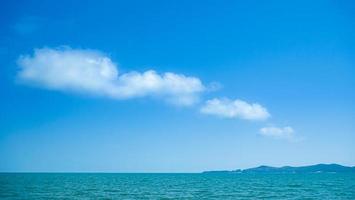 il fondale ha onde verde smeraldo e turchese. cieli azzurri e nuvole bianche. mare e isola in mezzo al mare. immagine per sfondo o sfondo foto