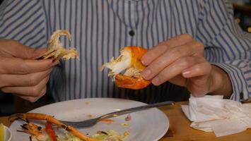 la mano di una donna sta sbucciando i gamberetti. i gamberi alla griglia erano sgusciati e pronti da mangiare. mangiare pesce al ristorante. foto