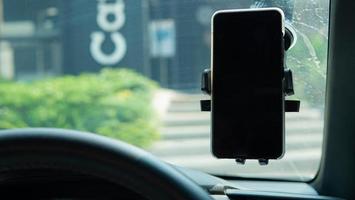 smartphone nel supporto del telefono veicolare per il viaggio e utilizzato la mappa gps. lo smartphone sulla maniglia del cellulare incollalo sul vetro dell'auto per la sicurezza durante l'uso durante la guida foto