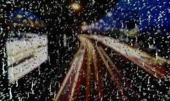 acqua piovana sul vetro in una giornata piovosa. gocce d'acqua sul vetro della finestra. con immagini di sfondo per il traffico sulla strada serale, c'è un semaforo sulla strada. rendering 3D foto