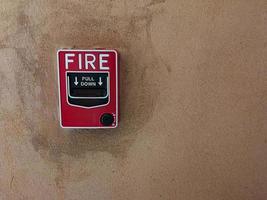 interruttore di allarme antincendio in vetro sul muro di cemento foto