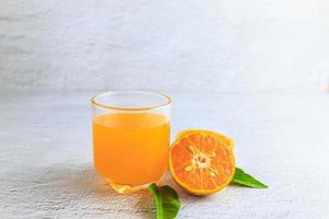 succo d'arancia appena spremuto in un bicchiere e agrumi freschi su sfondo bianco.