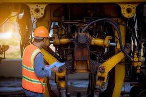 ingegnere ferroviario in fase di controllo del processo di costruzione test del treno e controllo dei lavori ferroviari sulla stazione ferroviaria con comunicazione radio. ingegnere che indossa l'uniforme di sicurezza e il casco di sicurezza sul lavoro. foto