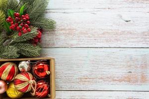sfondo di natale, ornamenti rossi e foglie di pino sul tavolo in legno per la decorazione festiva. foto