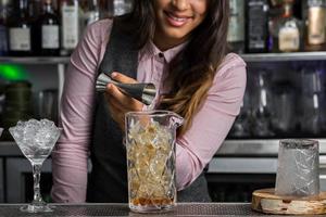 barista femminile con jigger che prepara cocktail foto