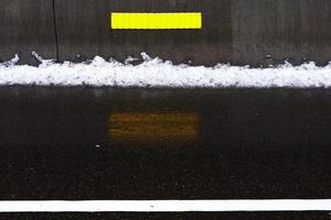 riflettore stradale giallo sulla strada con linea di neve. foto