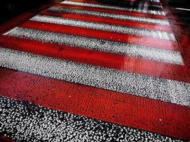 strada asfaltata bagnata con strisce pedonali rosse e bianche. foto