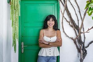 donna ispanica positiva in piedi vicino alla porta verde