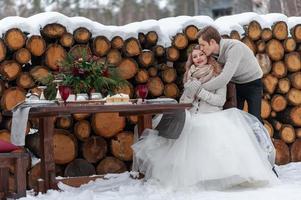 lo sposo abbraccia teneramente la sua sposa da dietro sullo sfondo della decorazione di nozze d'inverno foto