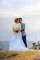 servizio fotografico di matrimonio di una coppia in riva al mare. abito da sposa blu sulla sposa. foto