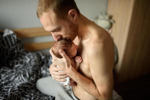 un padre tiene tra le braccia il figlio appena nato. foto