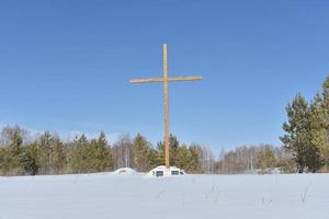 croce cristiana nel campo in inverno nella foresta foto