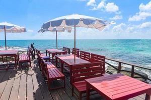 terrazza vista mare con tavolo e sedie in legno sulla spiaggia paesaggio natura con luce solare sull'ombrellone - balcone in legno vista mare idilliaco ristorante sul mare vicino al mare nel resort foto