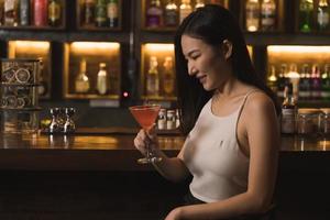 donna asiatica che beve un cocktail in un bar di notte. foto
