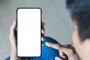 mockup copia spazio telefono, mano d'uomo che tiene smartphone con schermo bianco vuoto per la tua pubblicità e messaggio o contenuto informativo, cellulare sulla scrivania al bar. foto