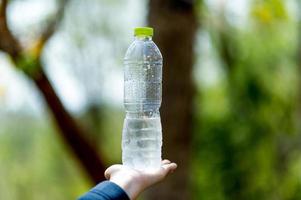 concetto creativo dell'acqua potabile della bottiglia d'acqua e della mano con lo spazio della copia foto