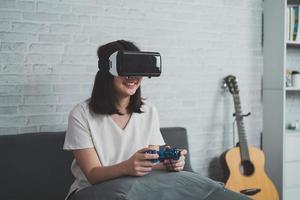 donna asiatica gioca al gioco vr per intrattenere a casa, donna asiatica gioiosa in casa in vacanza. donna felice che gioca al concetto di tecnologia metaverse vr. foto