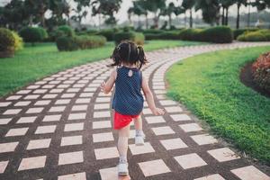 felice bambino asiatico ragazza sorridente. bambina che corre al tramonto felice bambina sorridente. bambina che corre al tramonto. bambina carina che corre al giardino del parco giochi. foto