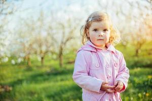 piccola bambina che corre tra alberi in fiore al tramonto. ar foto