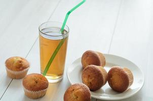 un bicchiere di succo di mela e pompelmo, tre muffin su un piatto e ancora tre muffin dolci ..colazione fresca al mattino. foto