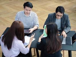 un gruppo di giovani gruppi di lavoro discute qualcosa mentre si siedono insieme al tavolo dello spazio di co-lavoro, strategia di pianificazione e brainstorming, colleghi che pensano al concetto foto